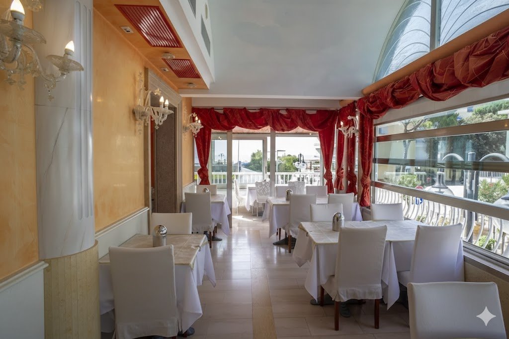 Restaurace hotelu Margherita v Lido di Jesolo v Itálii se světlým interiérem a výhledem, příjemné místo pro snídaně a večeře během dovolené u moře.