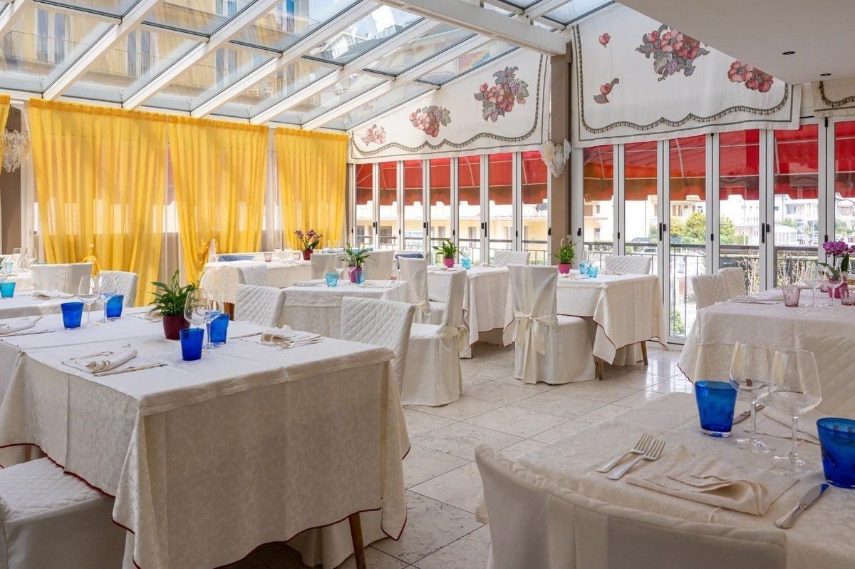 Hotelová restaurace hotelu Elpiro v Lido di Jesolo v Itálii s prostřenými stoly, možnost stravování během dovolené u moře.