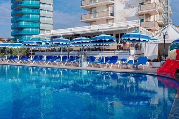Venkovní bazén hotelu Elpiro v Lido di Jesolo v Itálii s lehátky a slunečníky, hotel u pláže ideální pro letní dovolenou.