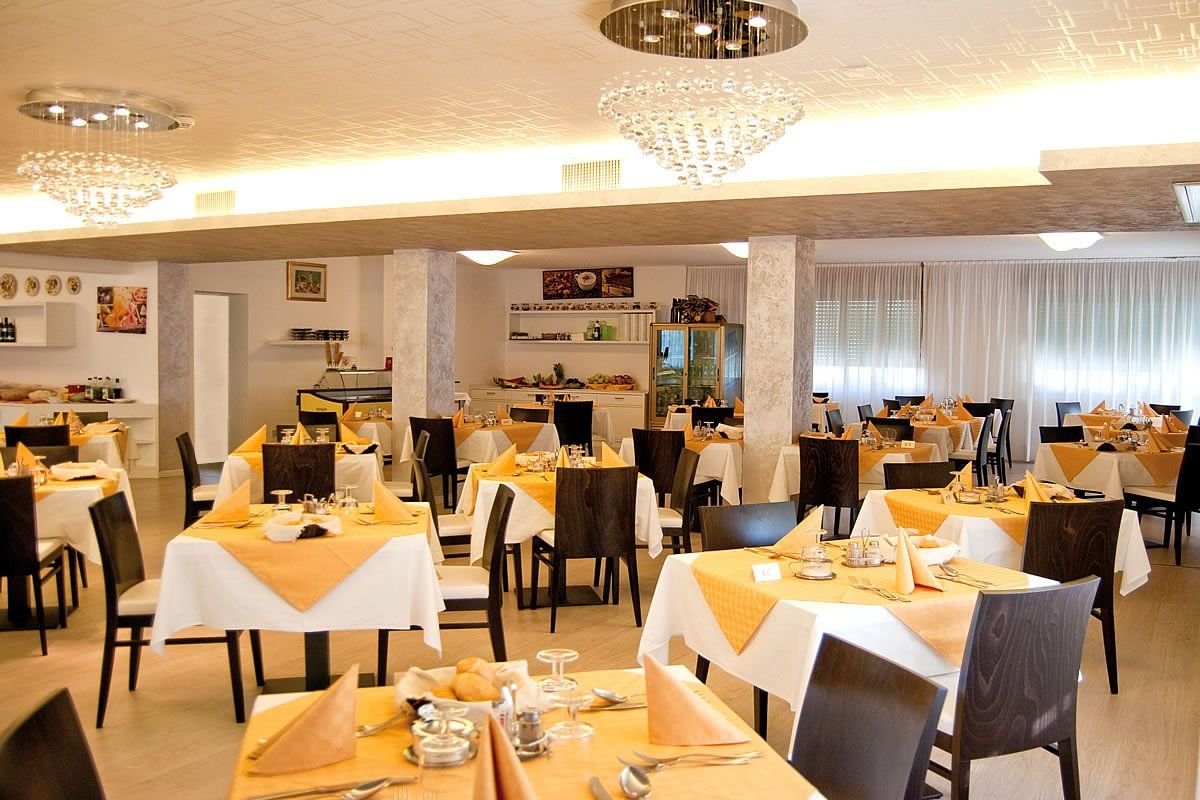 Hotelová restaurace v hotelu Old River v Lignano Riviera v Itálii s prostřenými stoly, možnost stravování během dovolené u moře.