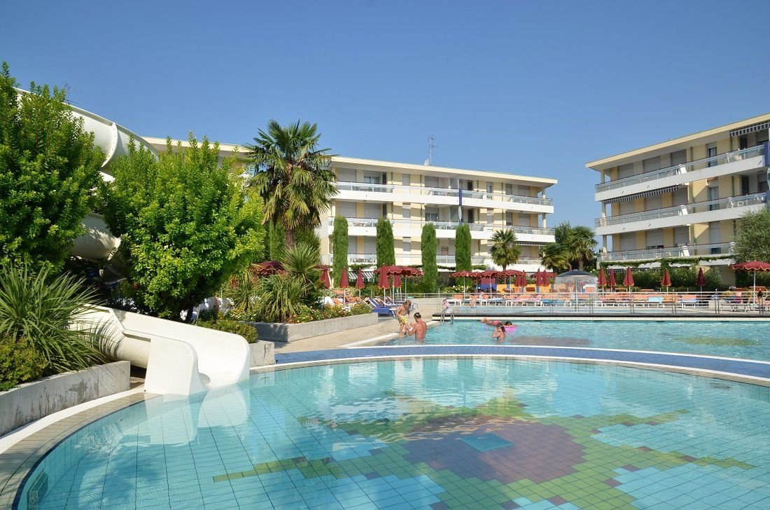 Bazén s dětským tobogánem ve villaggiu Planetarium Resort v Bibione v Itálii, apartmány s bazénem vhodné pro rodinnou dovolenou u moře.
